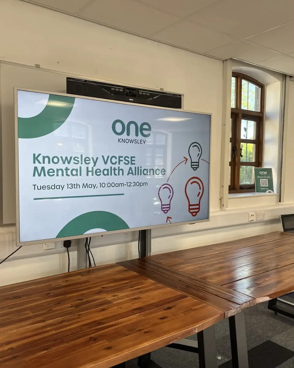 A meeting room set up for the Knowsley VCFSE Mental Health Alliance, with the agenda on a screen
