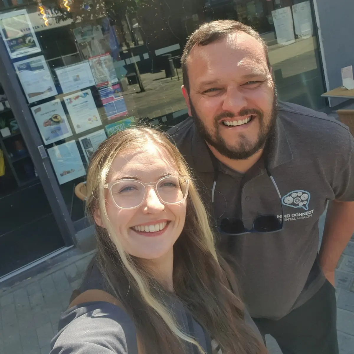Two members of the Mind Connect team smiling in a selfie outside a community building
